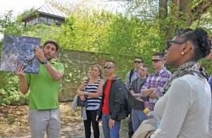 Photo by Carola MeuselChristian Gretz, tour guide at the Dachau Concentration Camp, shows a map of the former camp site to Stuttgart military community members on April 25. In the background, a replica of the former wall that surrounded the camp and one of eight watchtowers can be seen.  Some 82 service members of the Stuttgart military community visited Dachau during Days of Remembrance. The trip was organized by USAG Stuttgart’s Equal Opportunity and Religious Support offices.