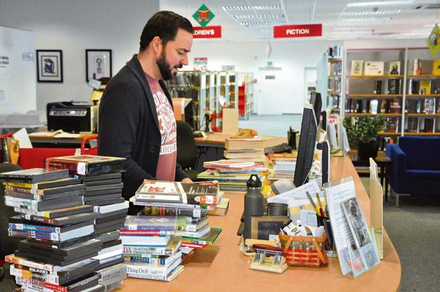 Library technician Ryan O’Neill checks in books and other materials for sorting and shelving at the Patch Library front desk.