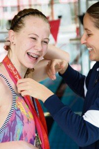 Jane Overslaugh RathbunKim Vandenburg, Olympic medalist, lets Stuttgart Piranhas swim team member Sarah Hutchinson try on a few of her medals.