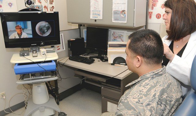Erica Taylor, nurse director for the Telehealth Program at Landstuhl Regional Medical Center, demonstrates using the Telehealth cart otoscope to conduct a real-time tympanic membrane exam. On screen is Physician Assistant Steven Cain, who from a remote location can see and evaluate the patient and provide an appropriate plan of care. -- Photo by Phil Jones.