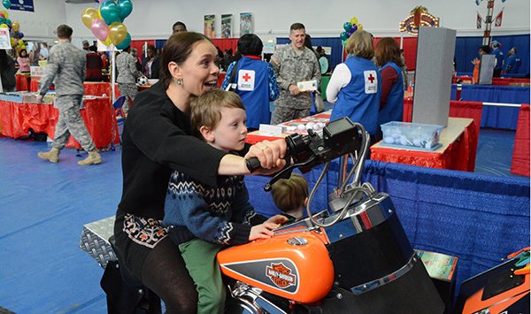 Dina Miller, with her 5-year-old son Kai Miller, enjoy some wild riding during a motorcycle video game that was one of many interactive games at the USAG Stuttgart Resiliency Carnival at Patch Fitness Center Feb. 5.