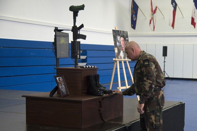 A representative from the Hungarian Special Forces, places a memento on the memorial of Sgt. 1st Class James Ginas III, during his memorial ceremony April 27 at Patch Barracks. U.S. Army photo by Visual Information Specialist Eric Steen .