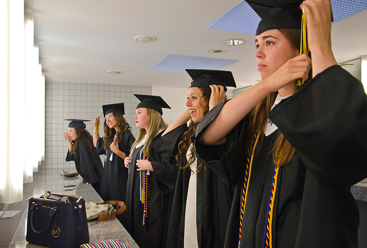 Seniors Madeleine Jones (from left), Gabriella Gante, Rachel Imlay, Bianca MacMullen and Kyle Hosler take care of last minute touch ups before the commencement exercise starts. Photo by S.J. Grady.