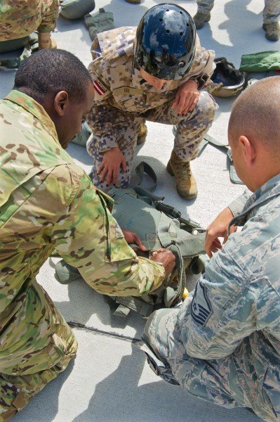 Military personnel from the Latvian National Armed Forces, U.S. Army and the U.S. Air Force inspect equipment during joint airborne training operations at Lielvarde Air Base, Latvia, June 15, 2015.