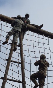 Three U.S. Soldiers assigned to 554th Military Police Company negotiate a cargo net obstacle during the annual 709th Military Police Battalion's D-Day Competition in the Boeblingen Local Training Area near Panzer Kaserne, Boeblingen, Germany Oct. 27, 2015.