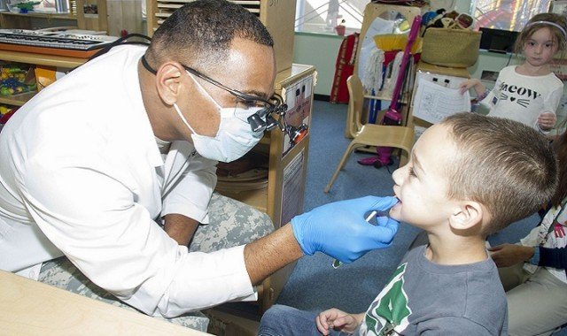 Maj. Demarcio Reed, commander of U.S. Army Dental Activity-Japan, conducts a dental screening Oct. 19 with Xavier Pittman, 5, in the Strong Beginnings Class at the Sagamihara Family Housing Area’s Child Development Center. (U.S. Army photo by Lance Davis)