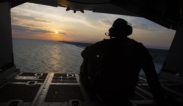 A U.S. Air Force loadmaster assigned to the 15th Special Operations Squadron watches the sunset from the back of an MC-130H Combat Talon II during Exercise Emerald Warrior 16, May 12, 2016, at Hurlburt Field, Fla. Emerald Warrior is a U.S. Special Operations Command sponsored mission rehearsal exercise during which joint special operations forces train to respond to real and emerging worldwide threats. (U.S. Air Force photo by Staff Sgt. Matthew B. Fredericks)
