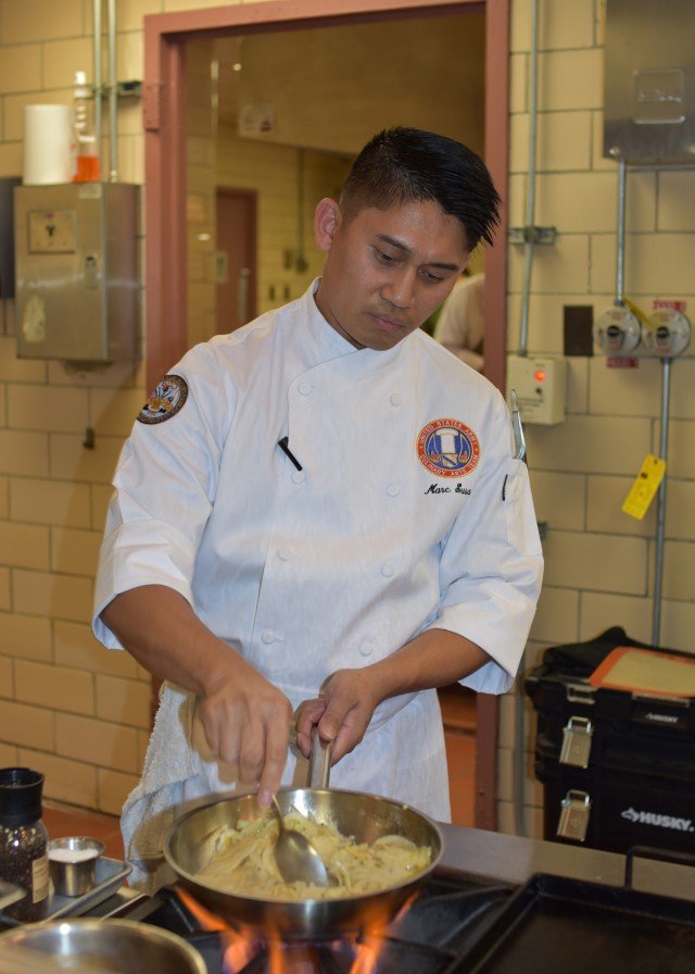 A chef prepares pasta in a skillet