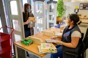 Librarian with face mask helps customer