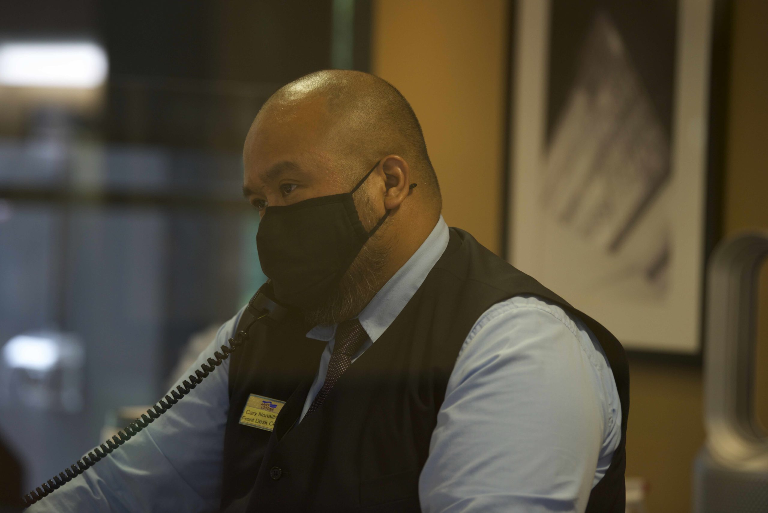 A masked hotel worker answers the phone