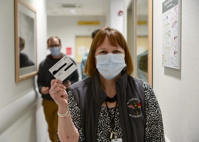 A person holding their COVID-19 vaccination card