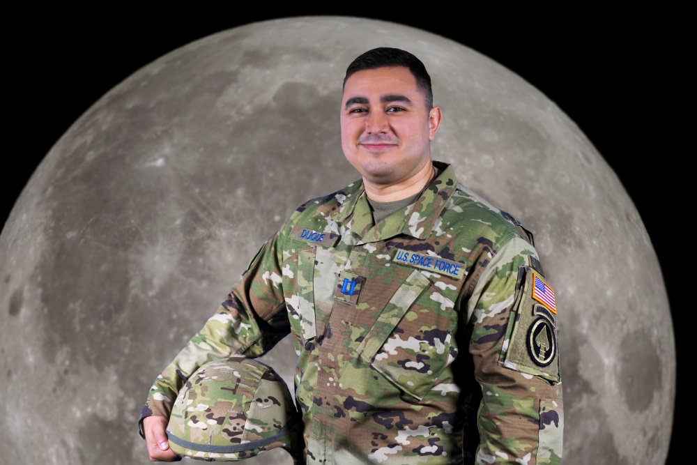 An officer stands in front of an image of the moon