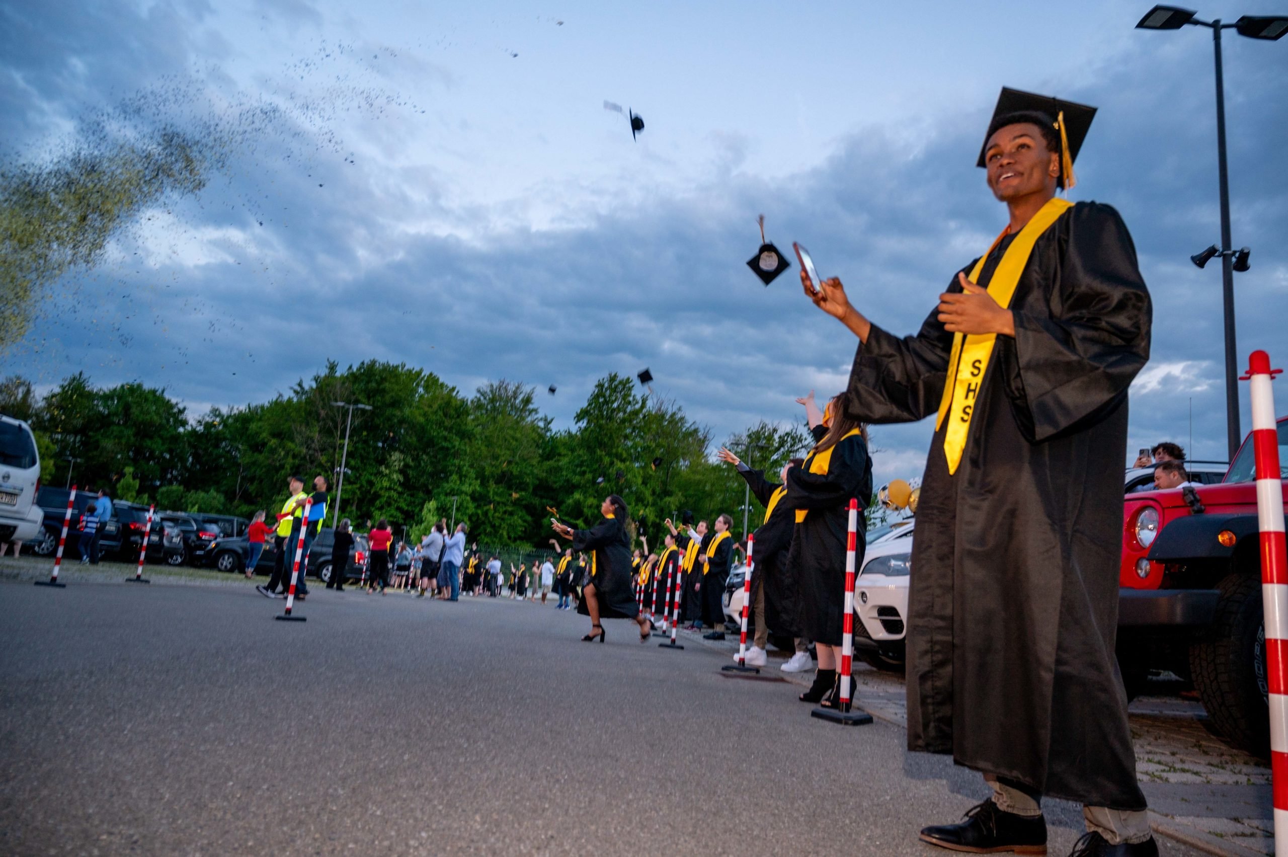 Stuttgart High School graduates toss their graduation caps during an outdoor, drive-in graduation ceremony at Panzer Barracks, Germany, June 2, 2021.