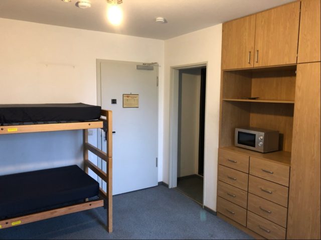 A hotel room with bunk beds and a microwave sits empty