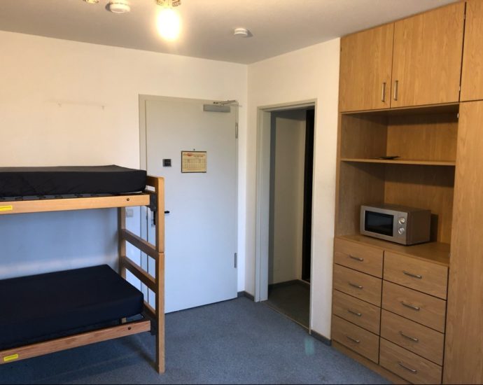 A hotel room with bunk beds and a microwave sits empty